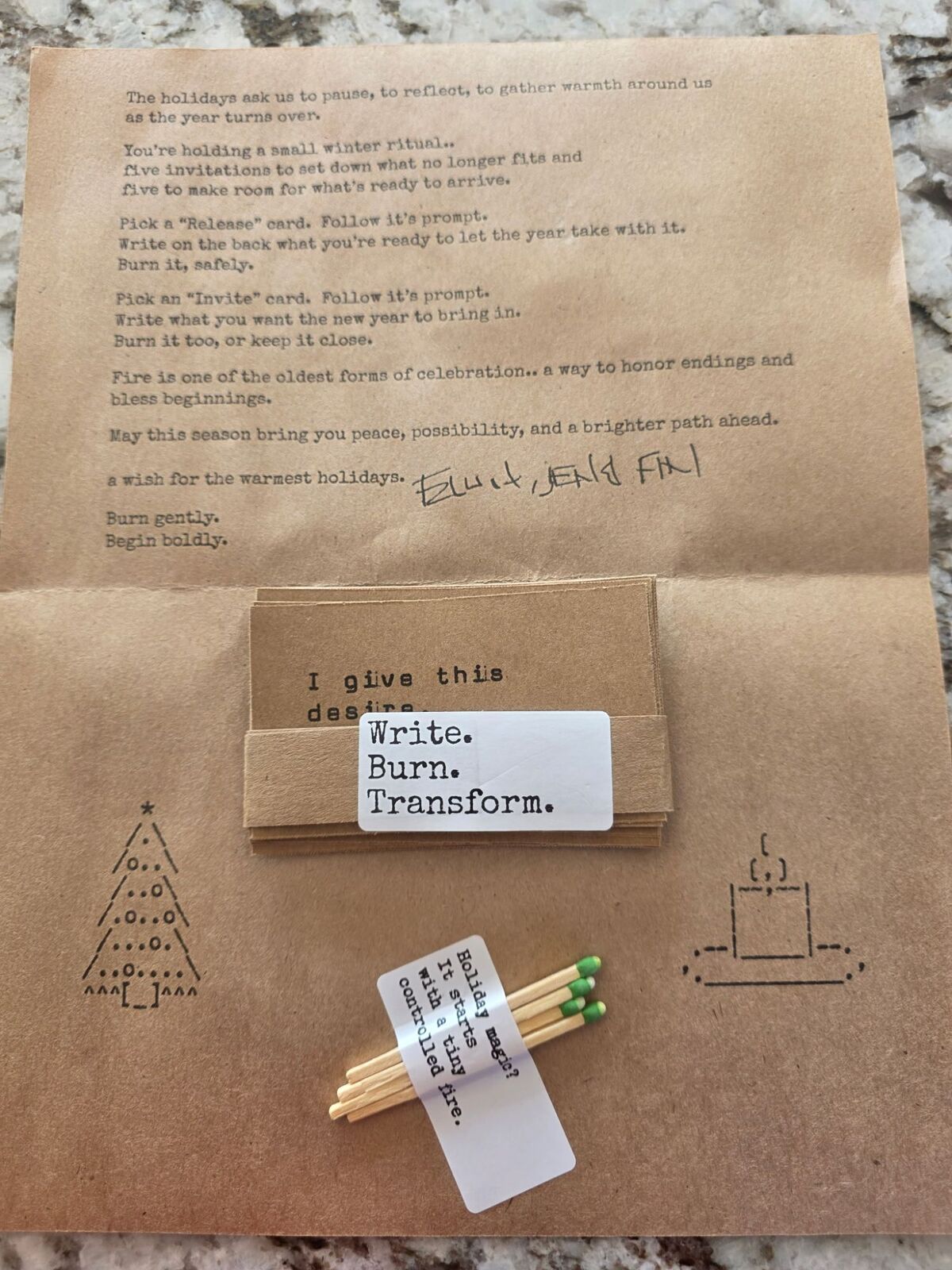 An opened kraft letter about a winter ritual, a banded stack of burn cards labeled Write. Burn. Transform., and a few green-tipped matches labeled Holiday magic? It starts with a tiny controlled fire.