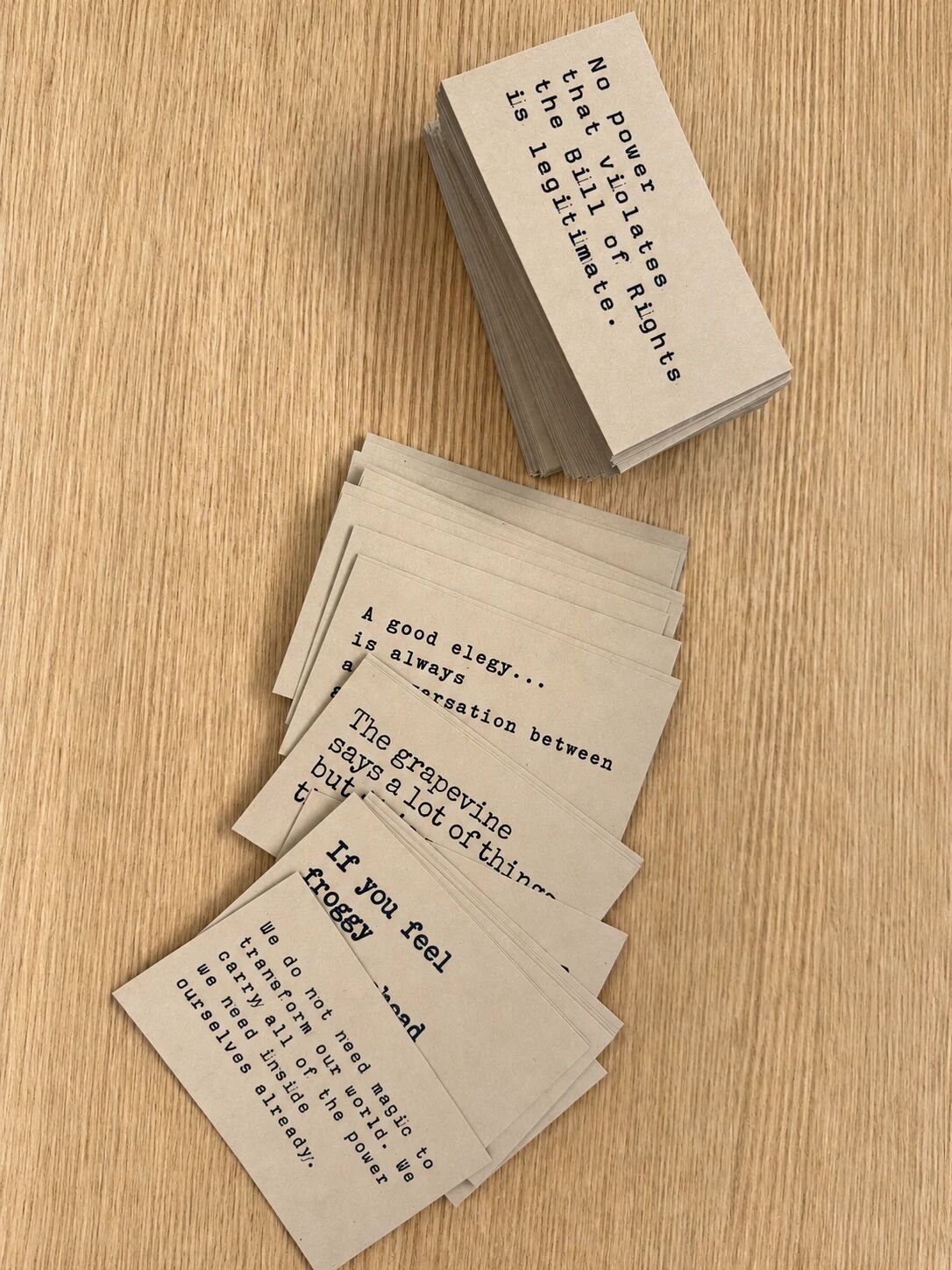 A tall stack and a loose spill of freshly cut kraft cards on a wooden desk